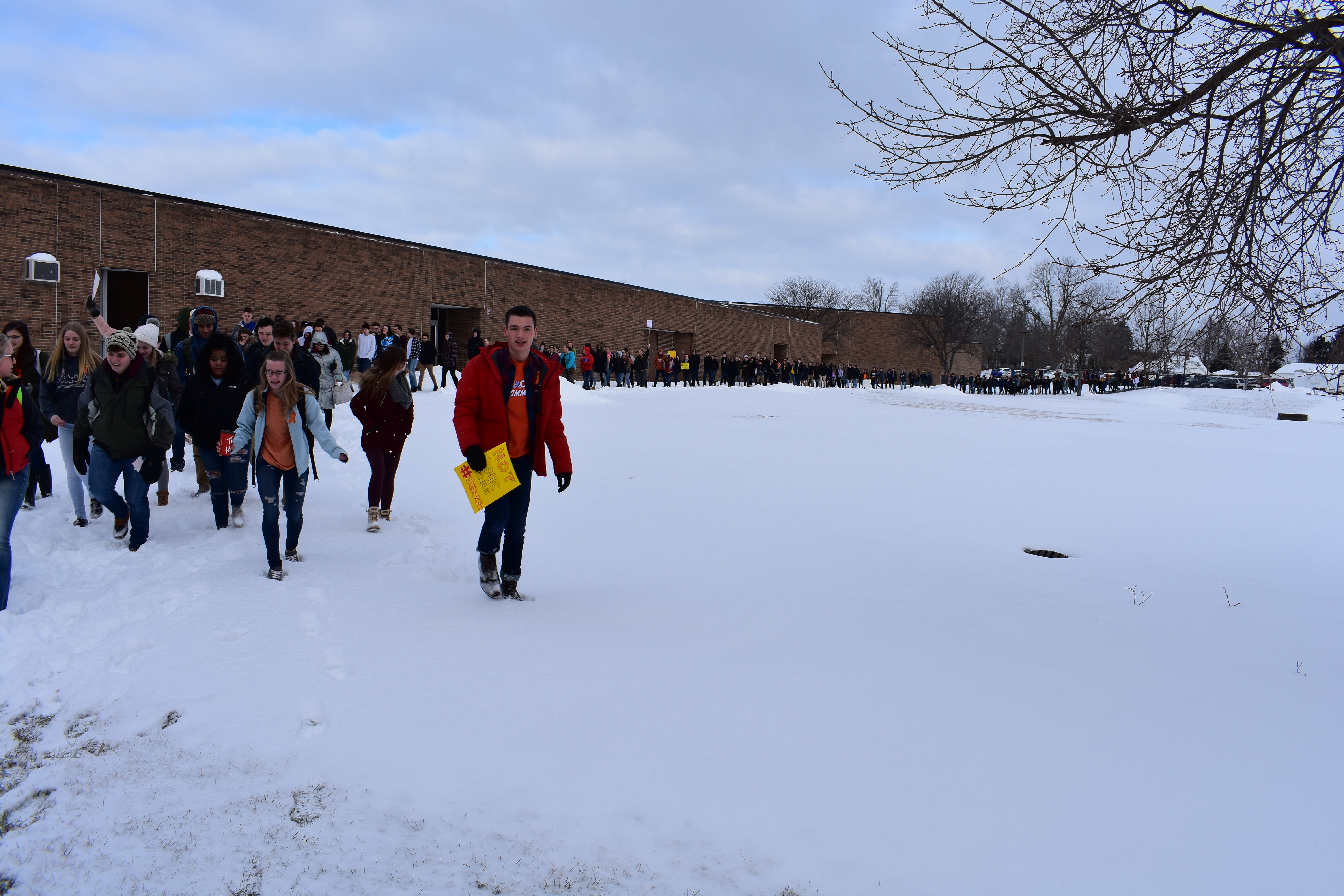 A line of hundreds of students walking in a line around the snow wrapped around the high school.